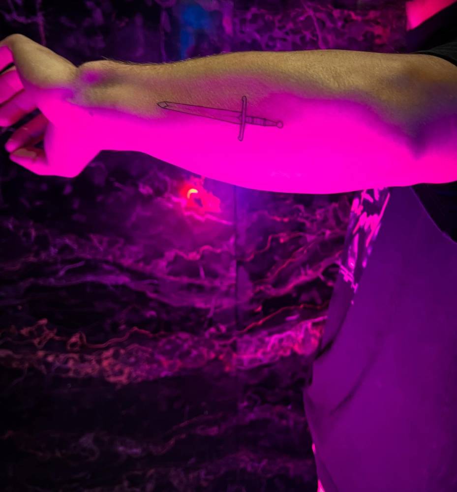 Sword tattoo in illustrative style located on the inner forearm.