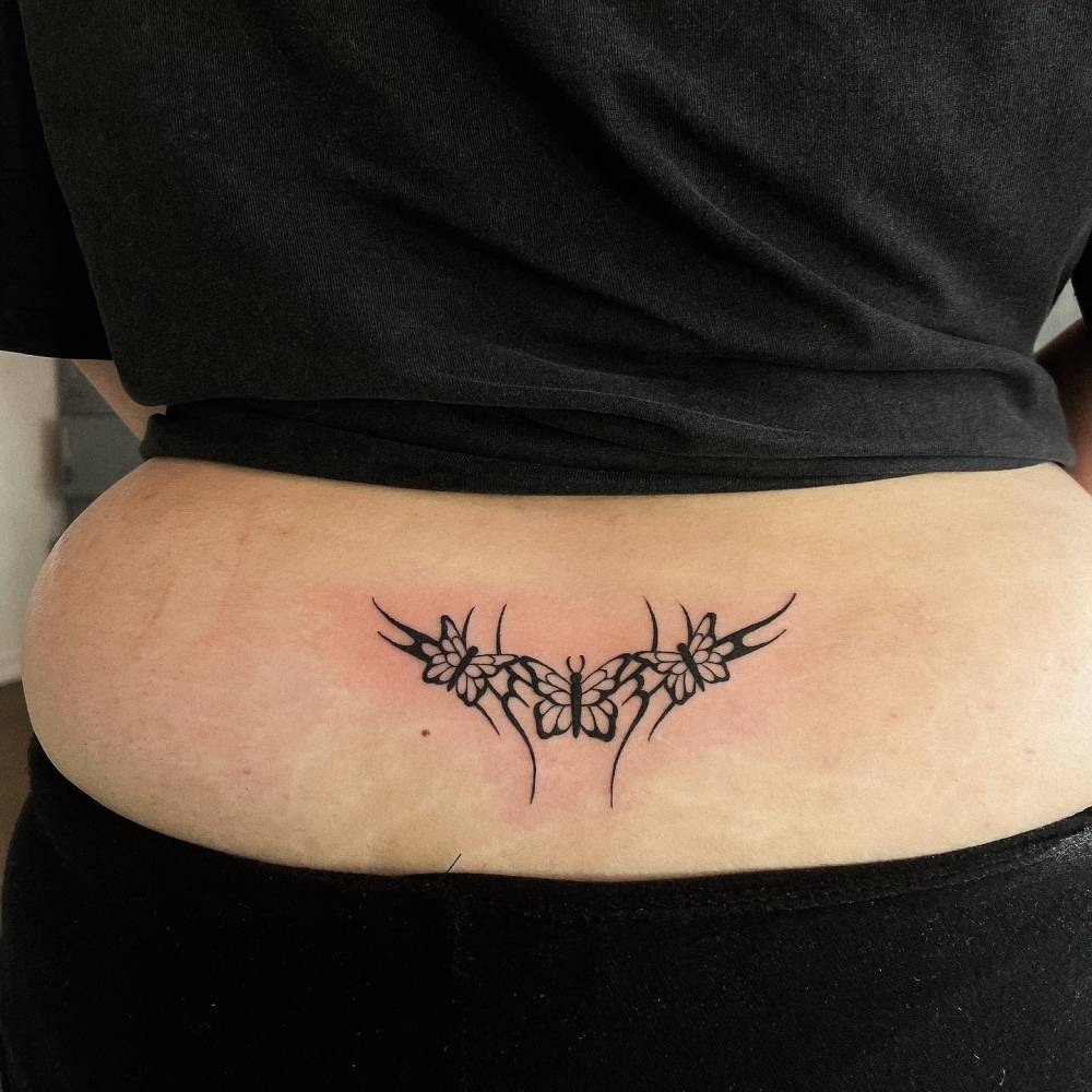 Tribal butterflies tattoo located on the lower back.