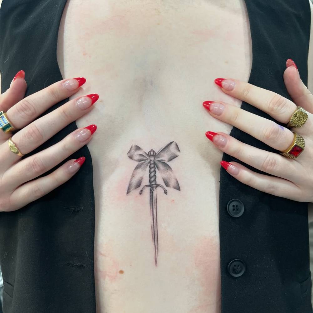 Dagger and bow tattoo located on the stomach, illustrative style.