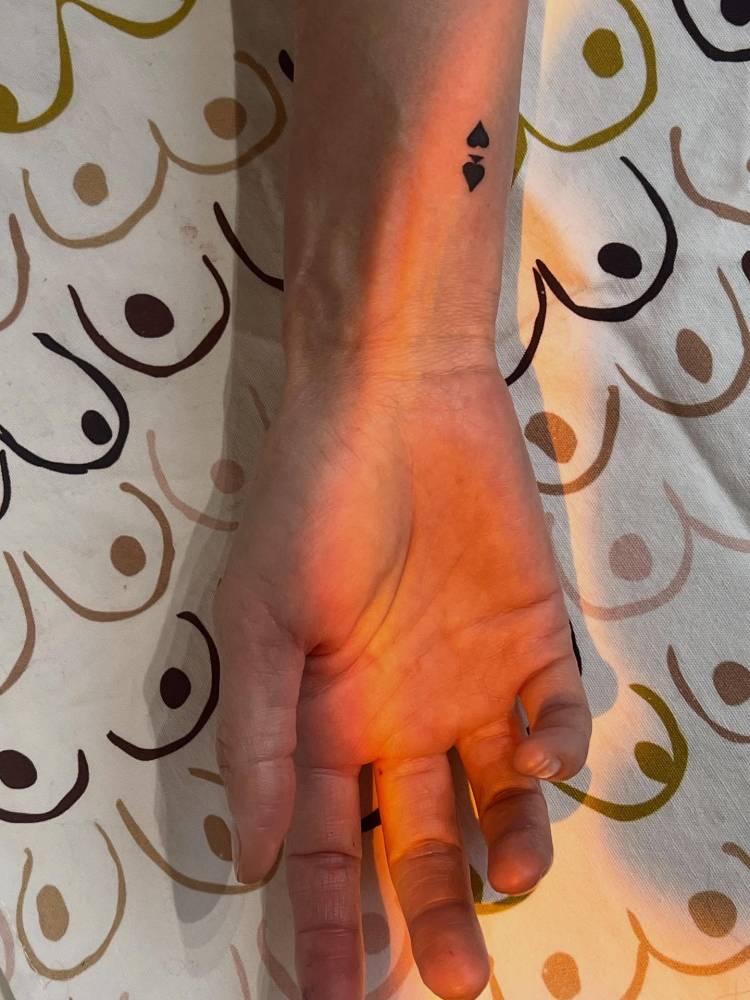 Spades and hearts suit tattoo located on the wrist, minimalistic style.