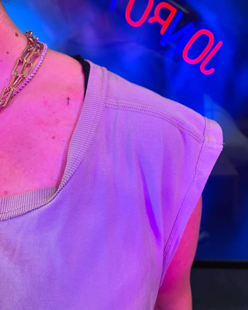 Cross tattoo in minimalistic style done on the collarbone.