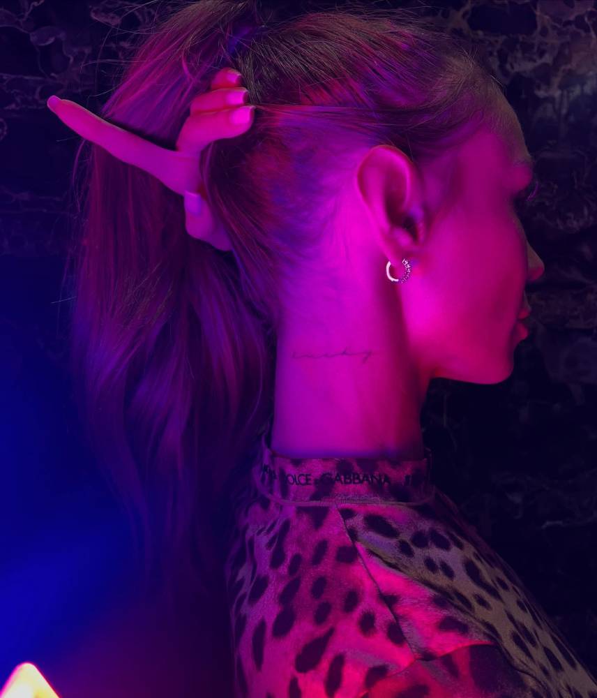 Word "lucky" in handwritten font tattooed on the neck.