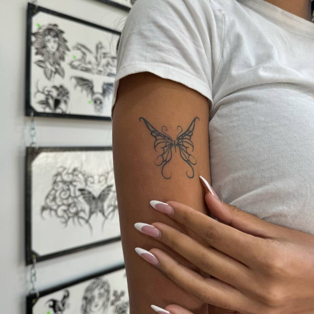 Tribal butterfly tattoo located on the upper arm.
