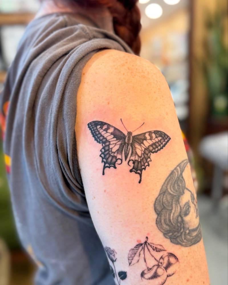 Butterfly tattoo located on the upper arm, illustrative style.