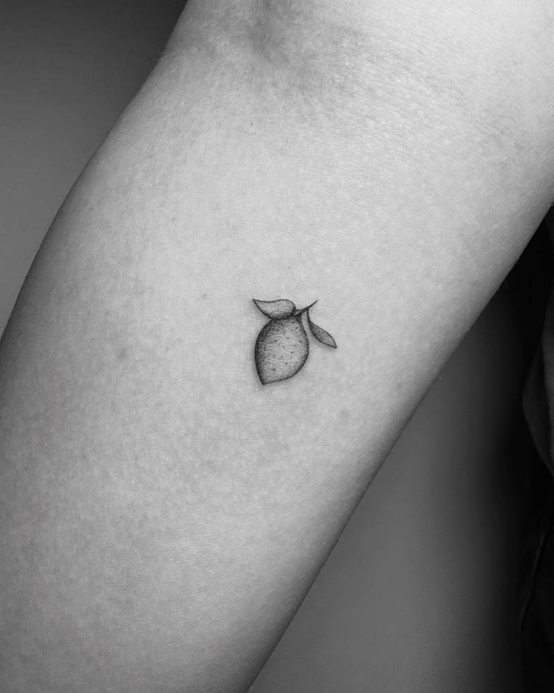 Tiny lemon tattoo in illustrative style located on the inner forearm.