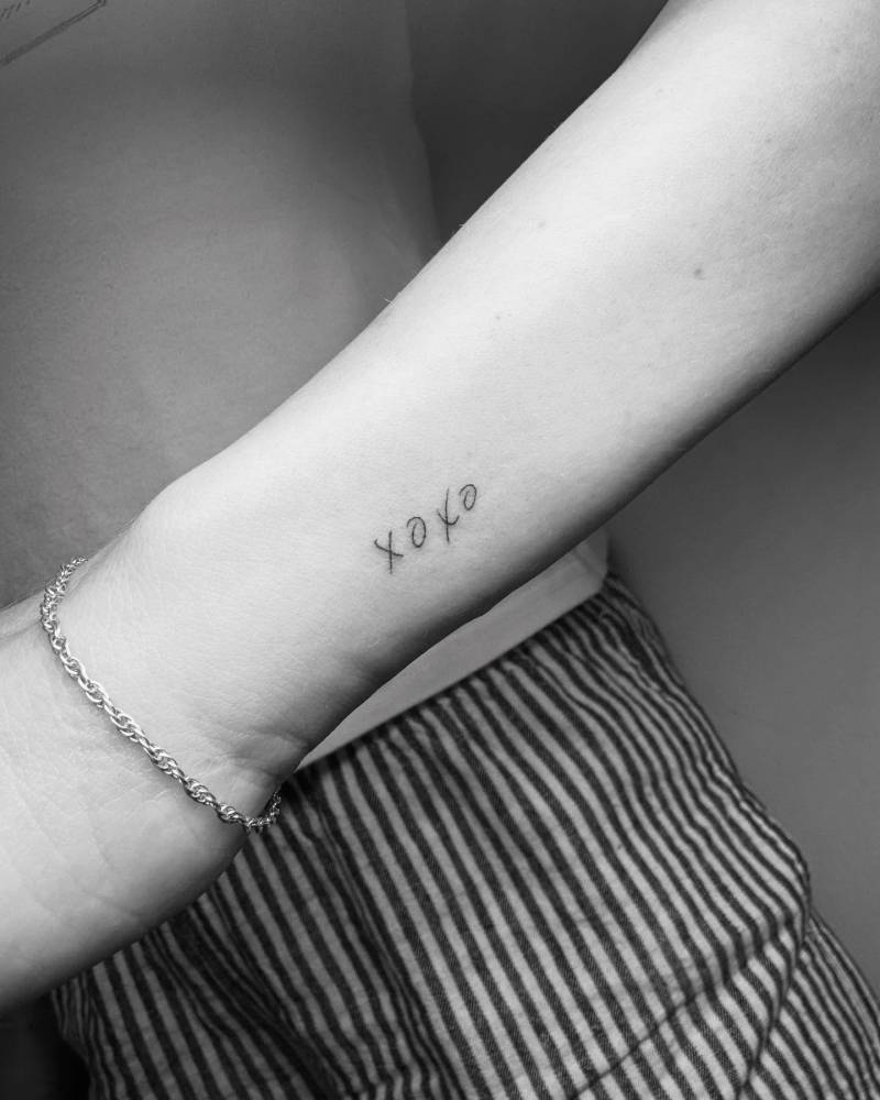 Handwritten font "xoxo" lettering tattoo placed on the wrist.