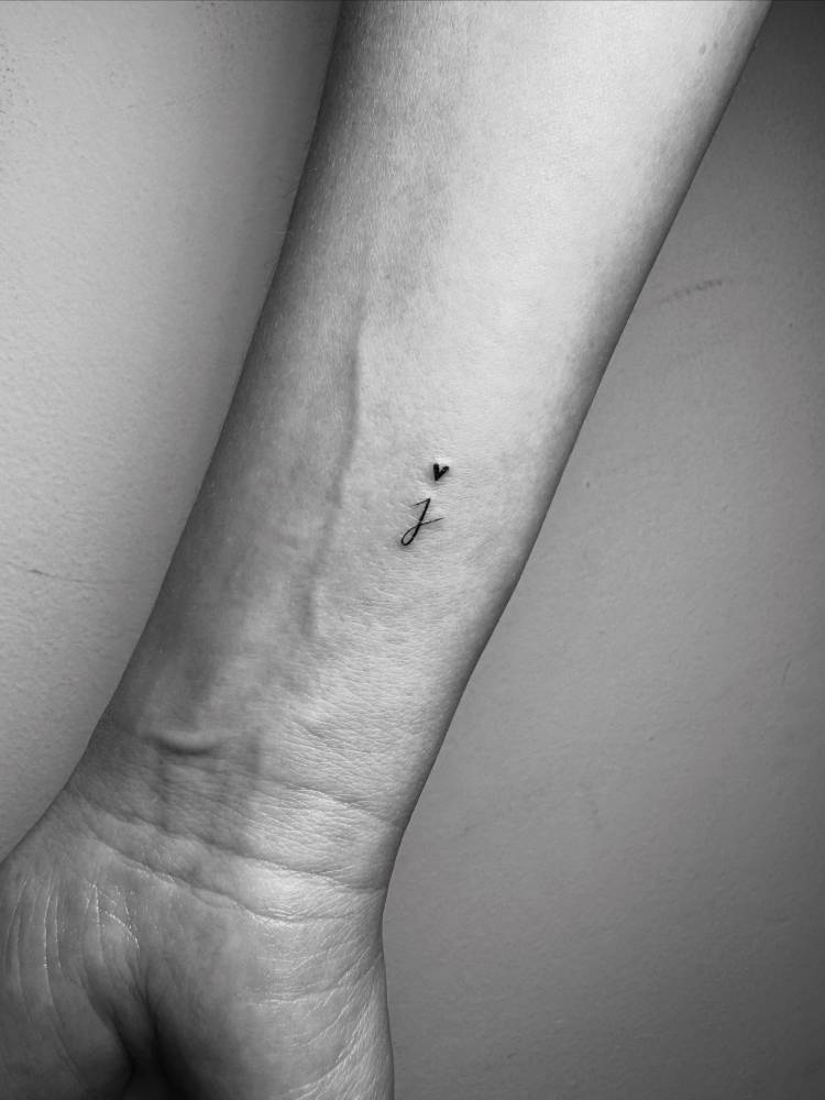 Letter "J" and tiny heart tattooed on the wrist.