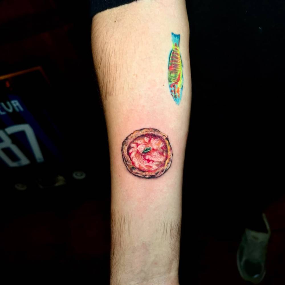 Margherita pizza tattoo in micro-realistic style located on the inner forearm.