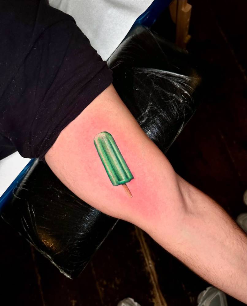 Ice pop tattoo located on the inner arm, done in micro-realism.