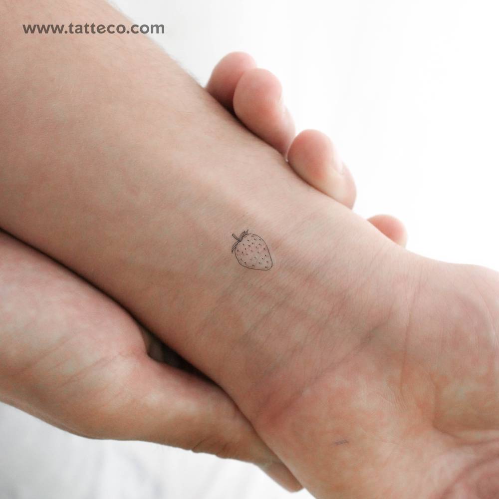 Little fine line strawberry temporary tattoo located on the wrist.