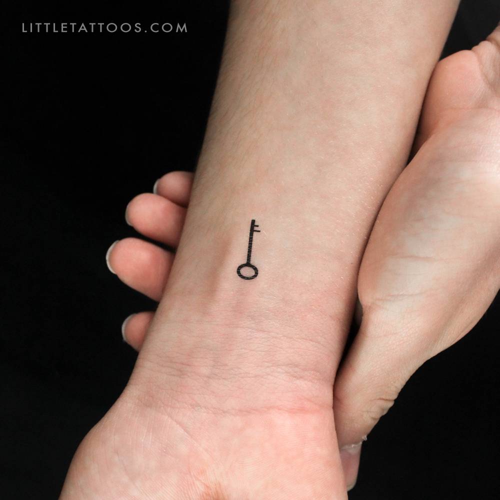 Tiny minimalistic key temporary tattoo located on the wrist.