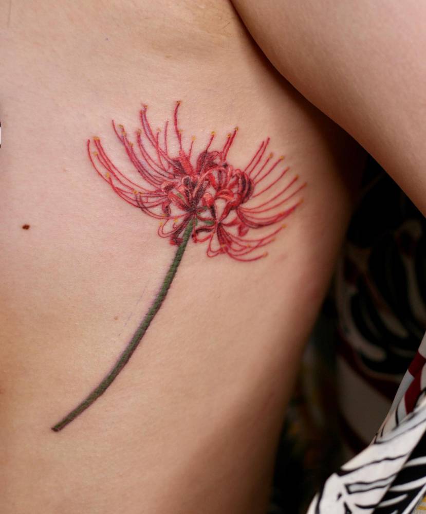 Red spider lily tattoo located on the side boob, watercolor style.