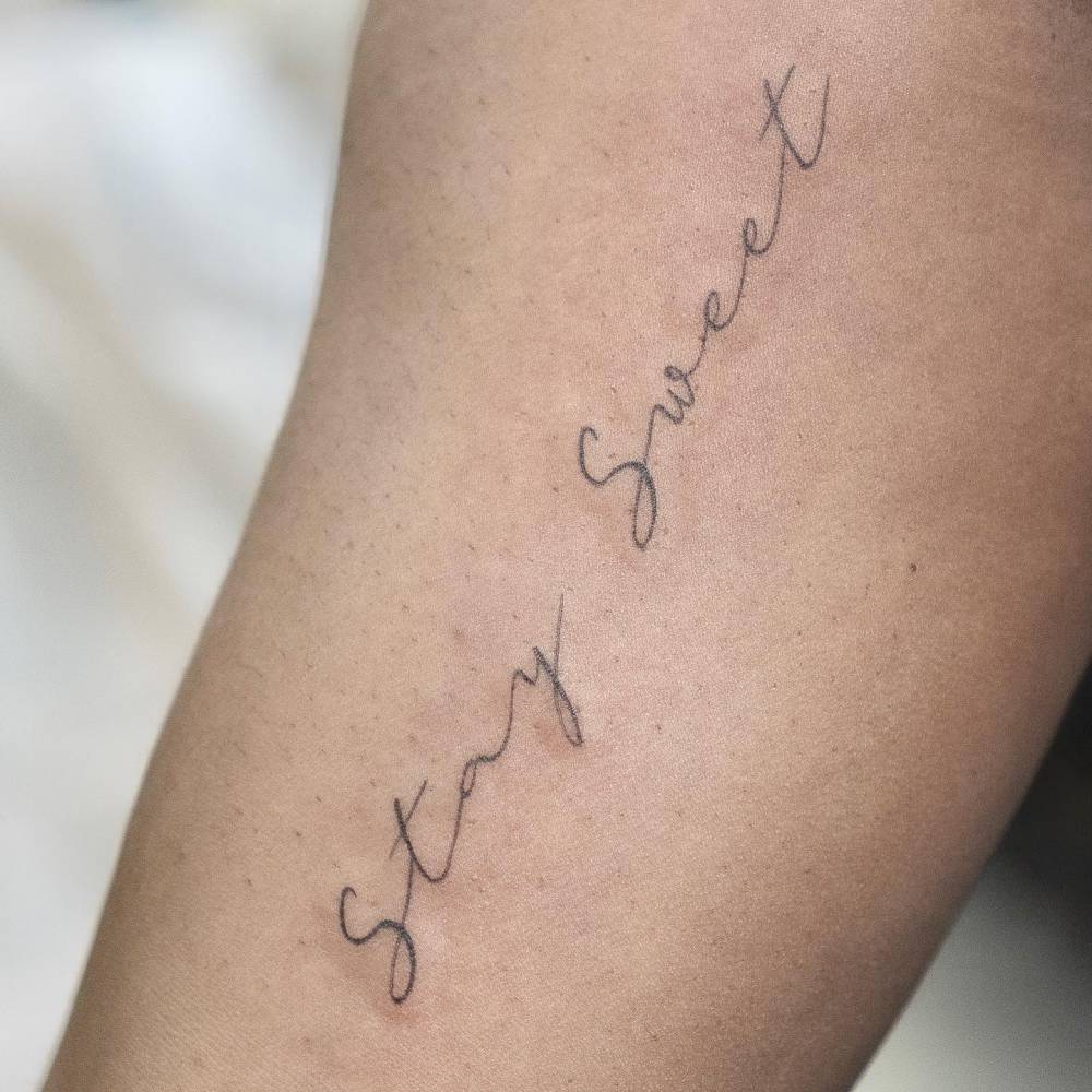 Tattoo that says "stay sweet" handwritten on the inner arm.