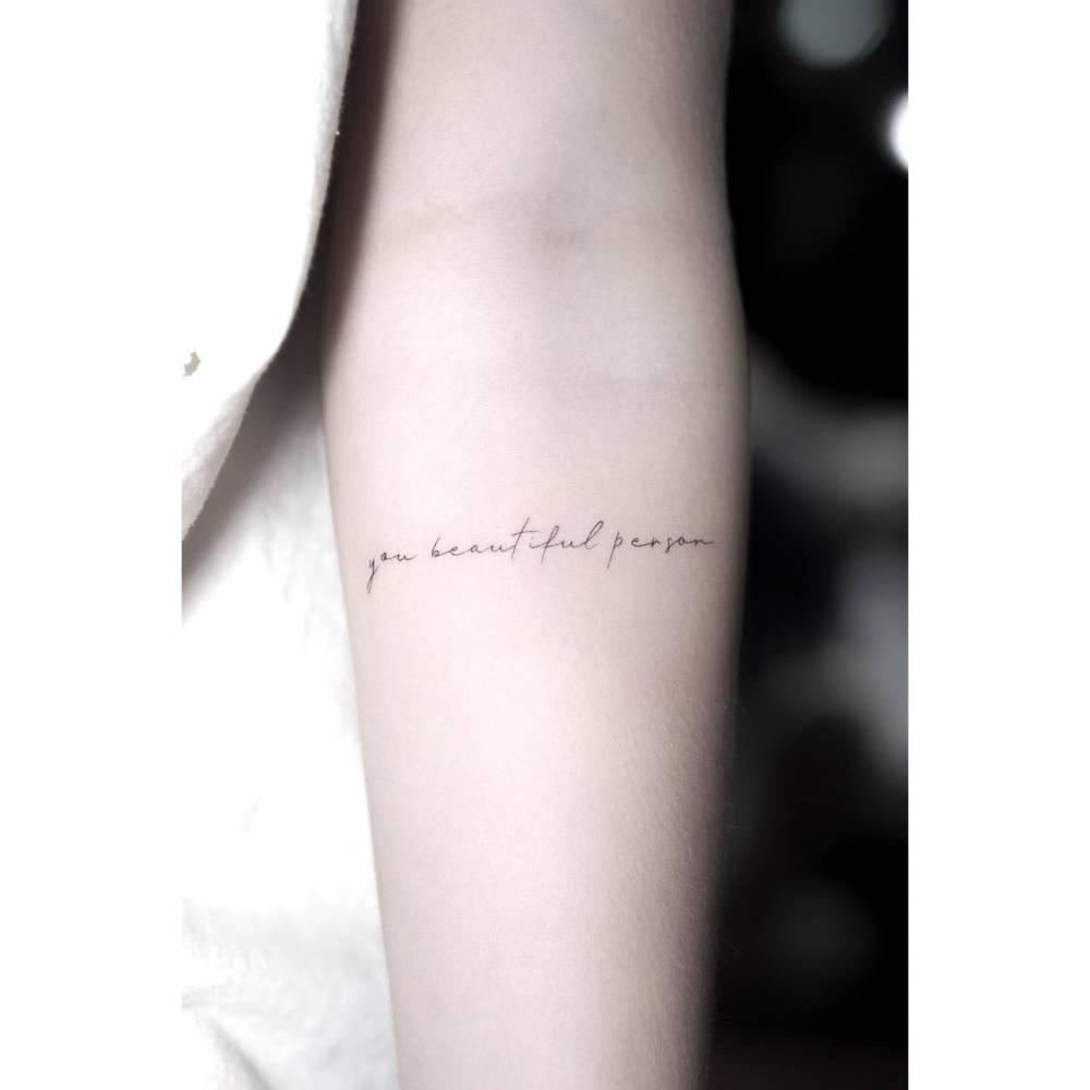 "You beautiful person" lettering tattoo on the inner forearm.