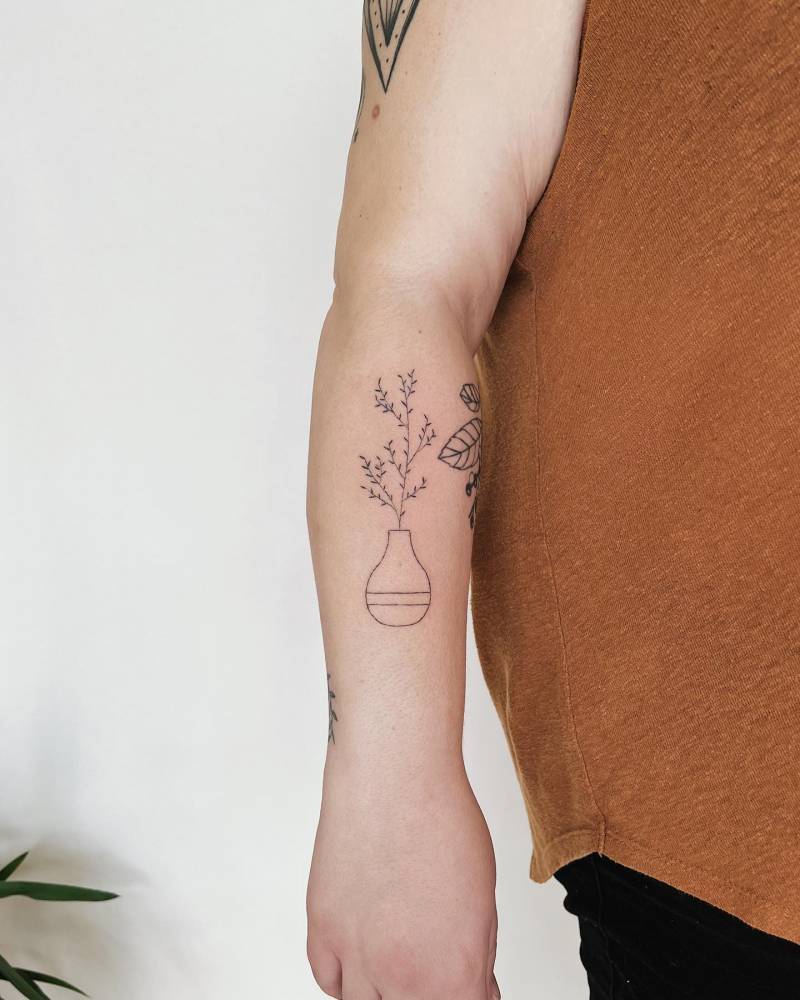 Hand poked plant and vase tattoo located on the forearm.