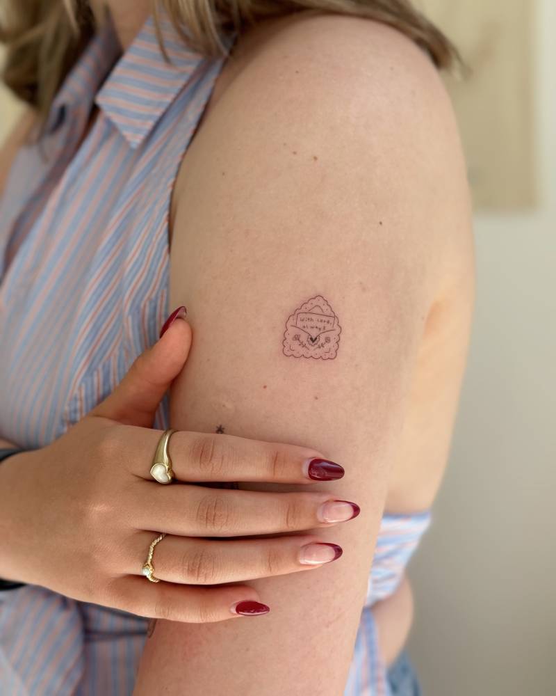 Fine line style love letter tattoo located on the upper arm.