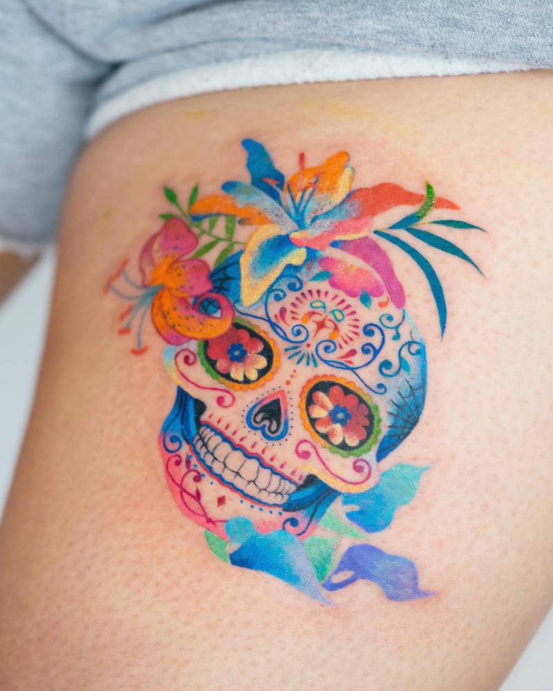 Colorful sugar skull tattoo located on the thigh.