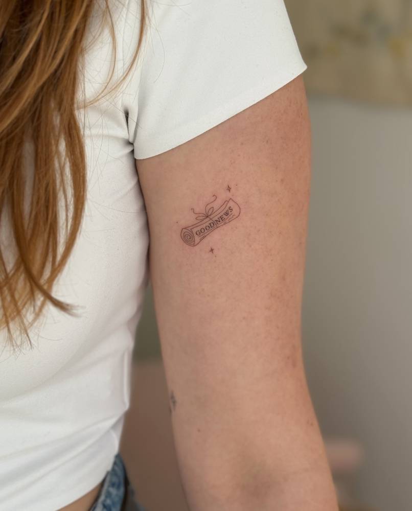 Fine line style newspaper tattoo done on the upper arm.