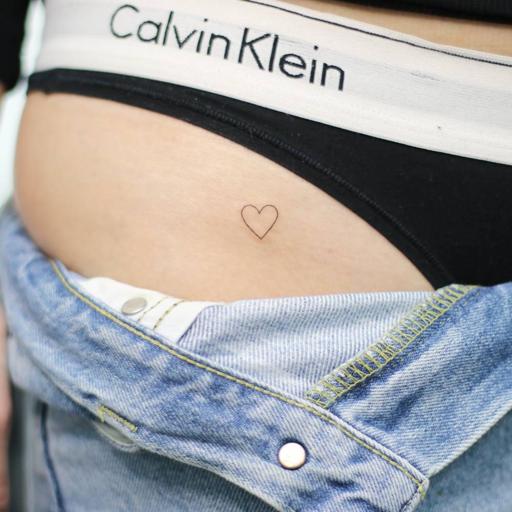 Minimalistic style heart tattoo located on the pelvis.