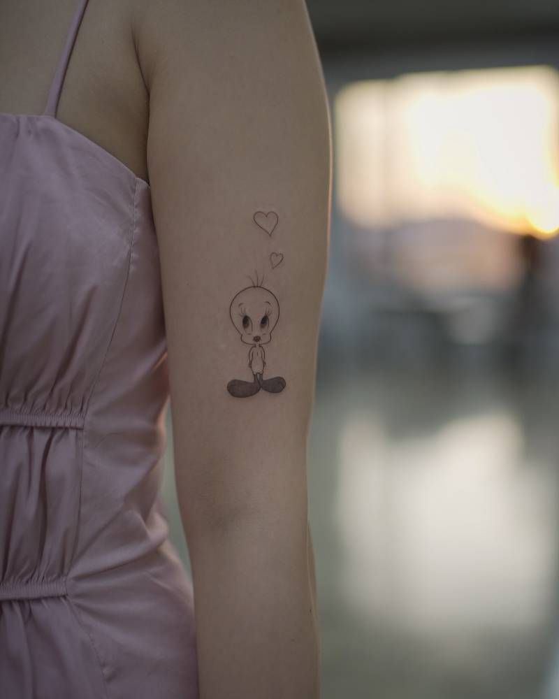 Cartoon style Tweety tattoo located on the upper arm.