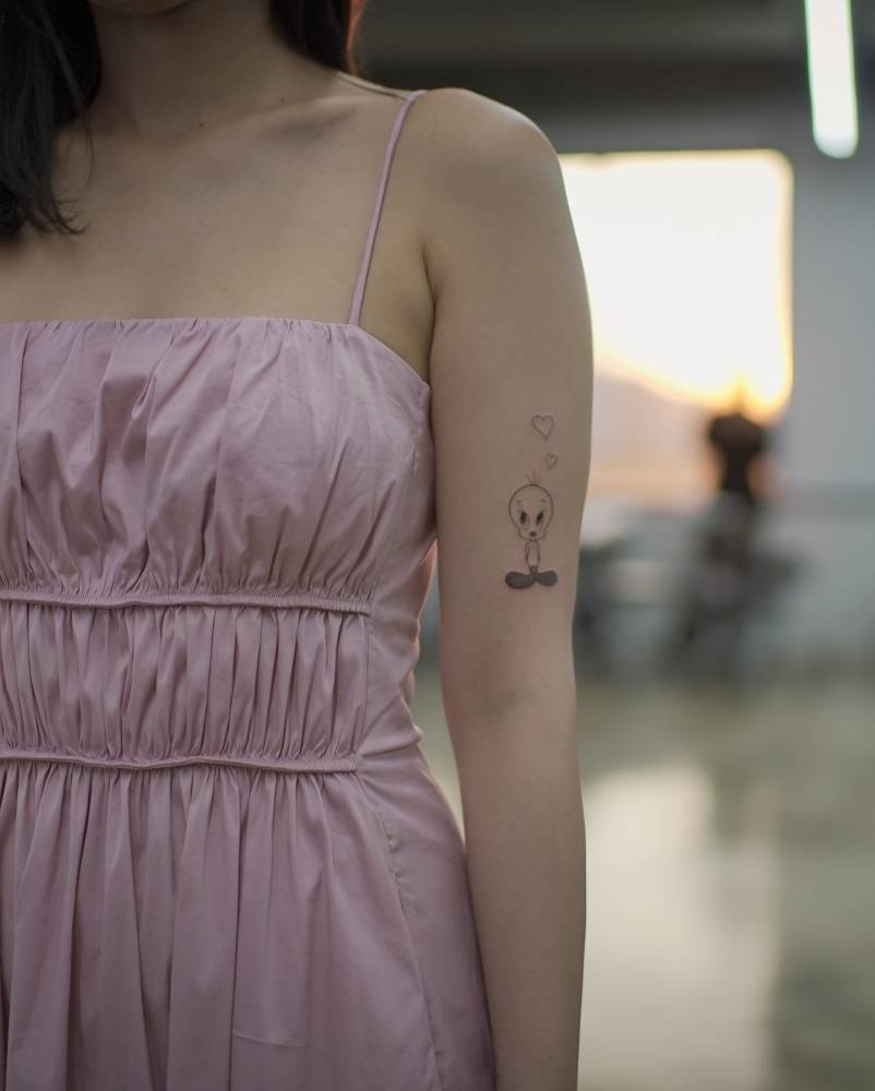 Cartoon style Tweety tattoo located on the upper arm.