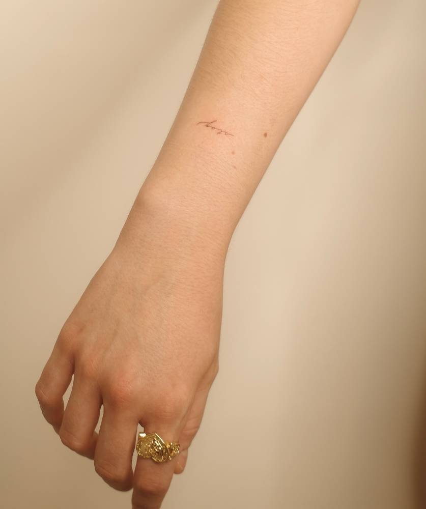 Handwritten tattoo of the word "stay" located on the wrist.