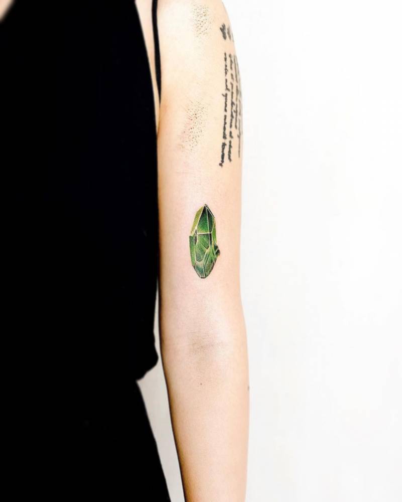 Micro-realistic emerald tattoo on the bicep.