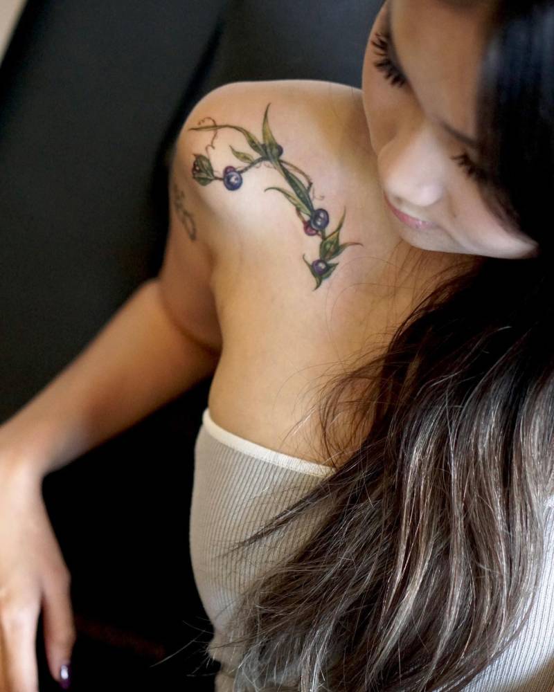 Watercolor style blueberries tattoo located on the shoulder.