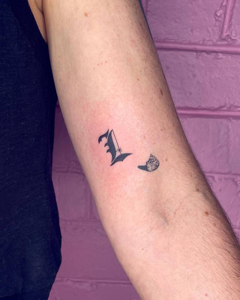 Gothic letter "L" tattoo hand poked on the bicep.
