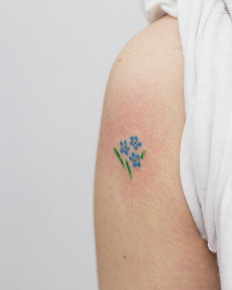 Forget-me-not tattoo located on the upper arm, watercolor style.