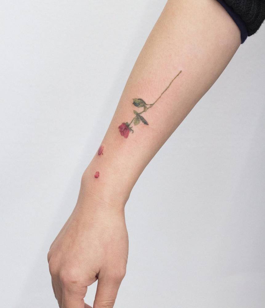 Watercolor style red rose tattoo done on the forearm.