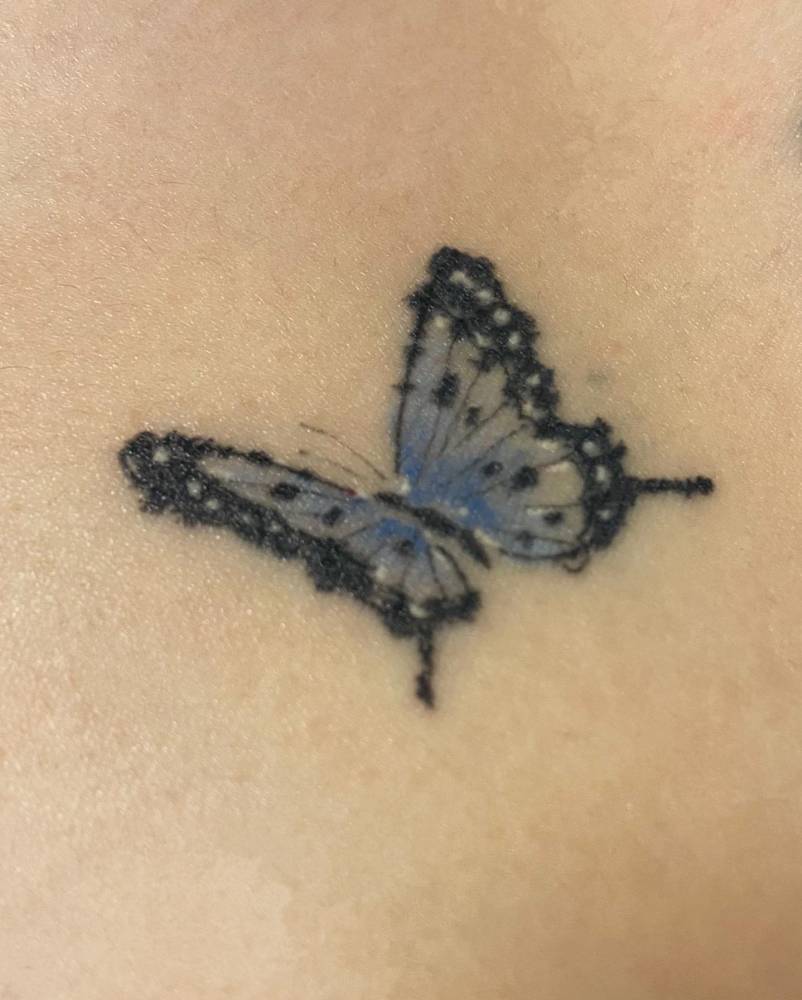 Healed watercolor style butterfly tattooed on the shoulder.