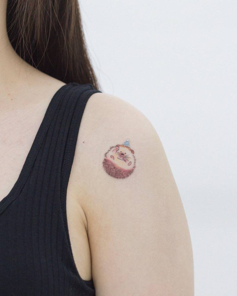 Cute hedgehog tattoo located on the shoulder.