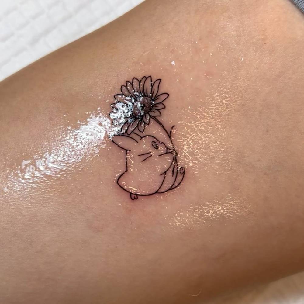 Chuu Totoro and sunflower tattoo located on the inner arm.