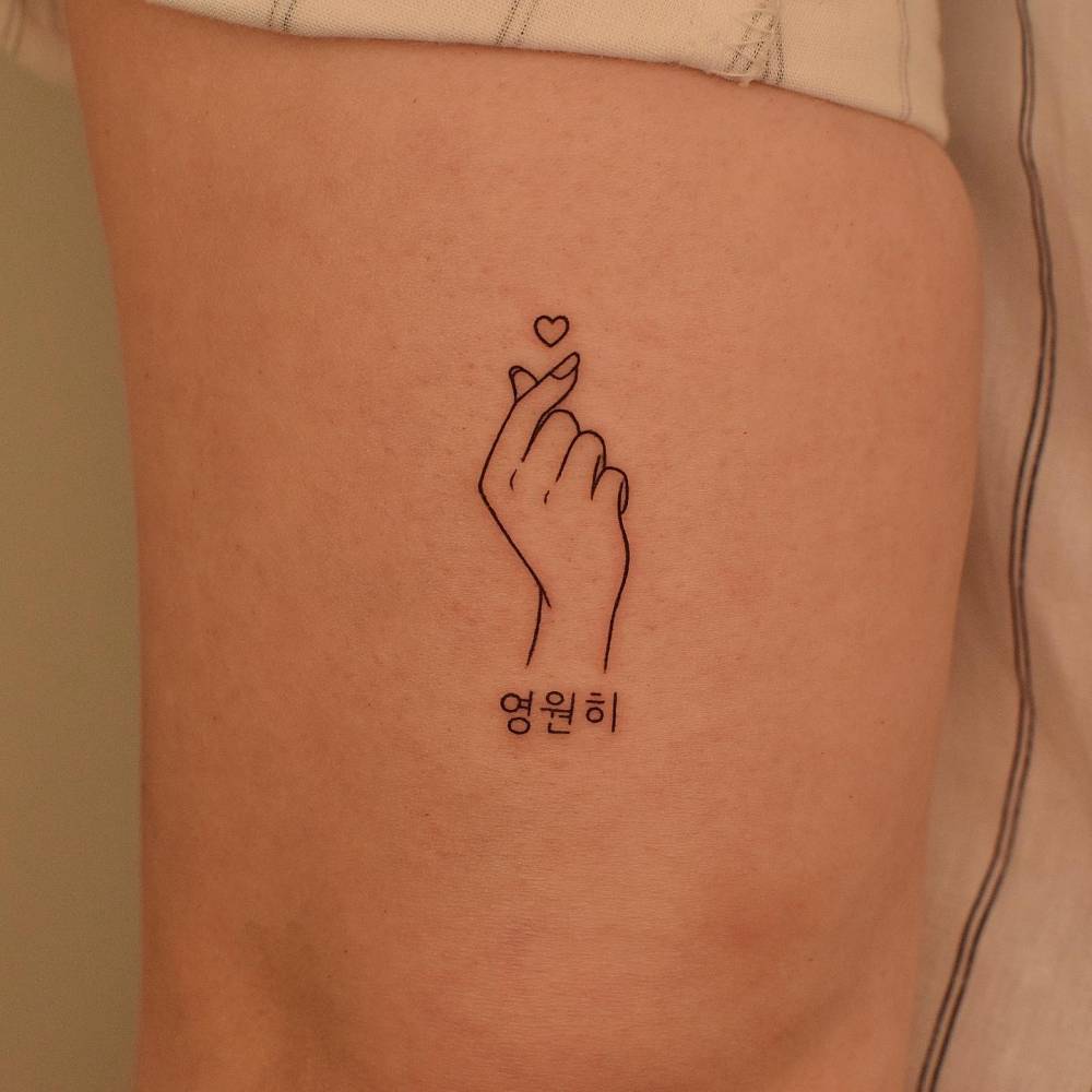 Korean finger heart tattoo located on the tricep, fine line style.