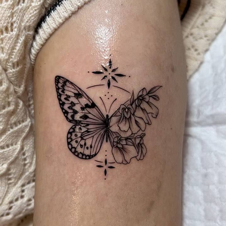 Illustrative style half butterfly half flower tattoo done on the upper arm.