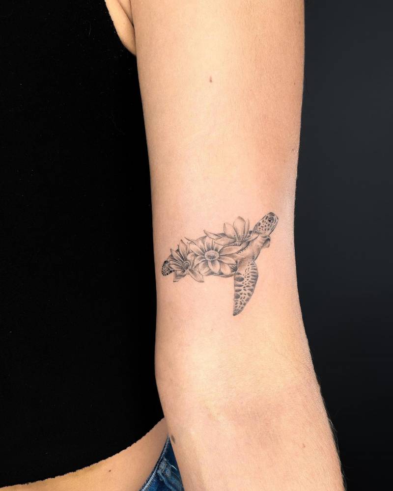 Micro-realistic turtle and flowers tattoo located on the bicep.