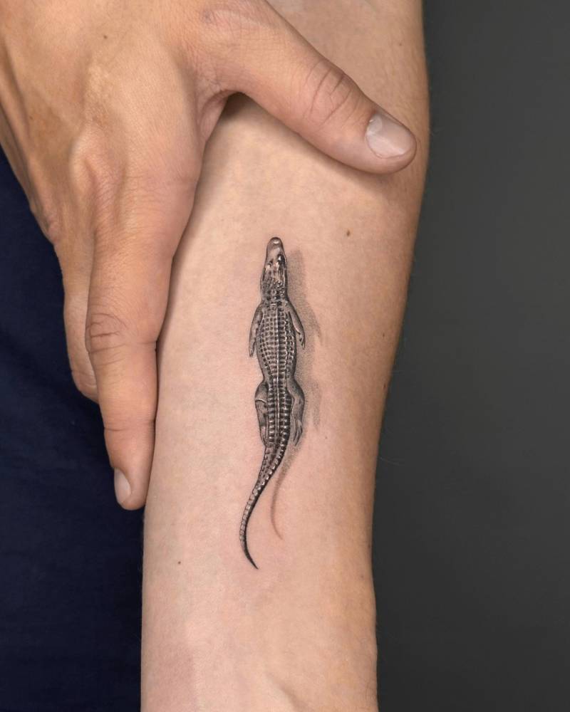 Micro-realistic crocodile tattoo located on the inner forearm.