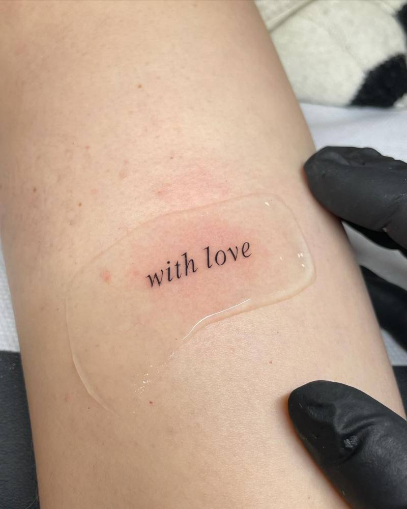 "With love" lettering tattoo located on the tricep.