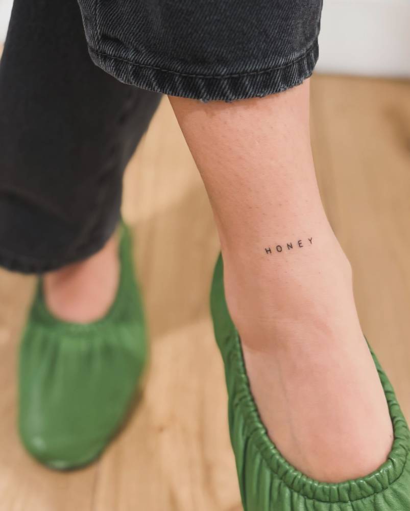 Hand poked little word "honey" tattooed on the ankle.