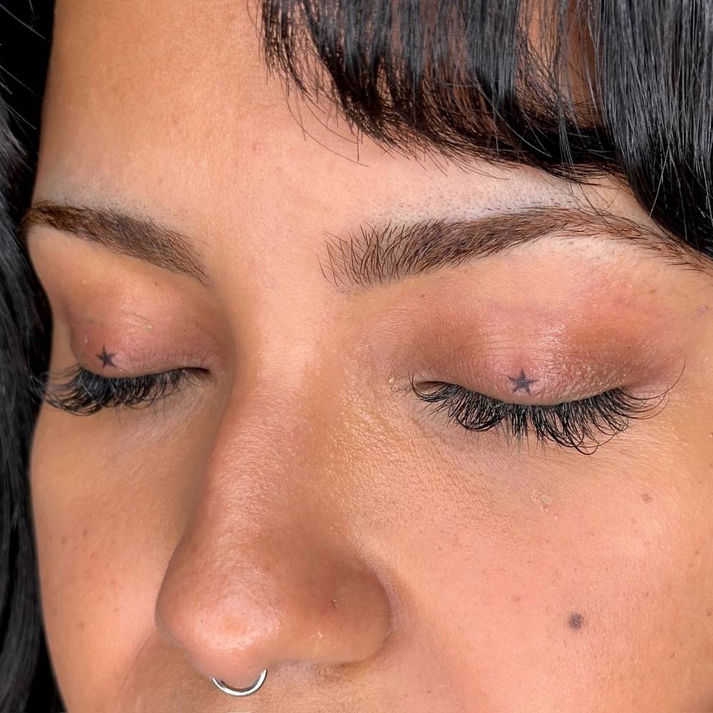 Hand poked minimalistic stars tattooed on the eyelids.