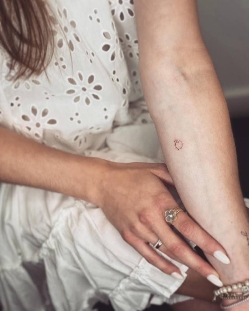 Tiny minimalistic apple tattoo located on the inner forearm.