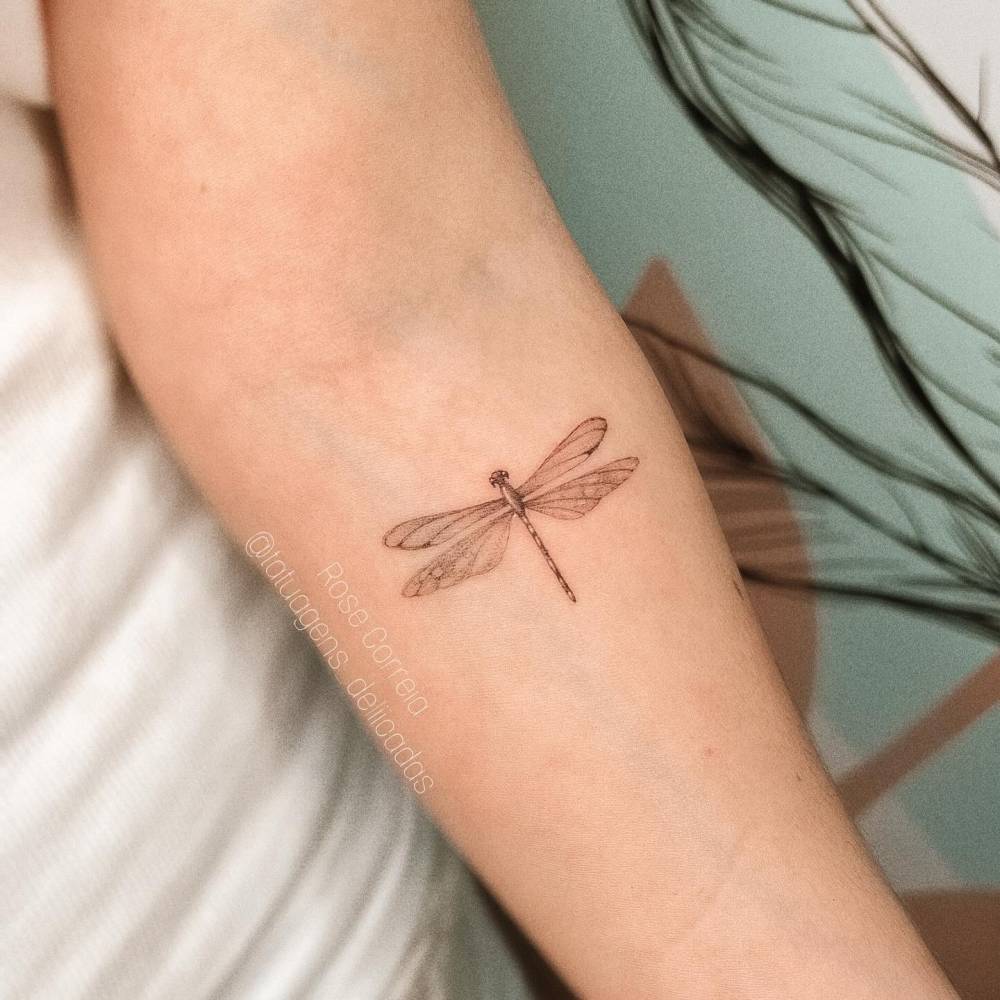 Illustrative style dragonfly tattoo located on the inner forearm.