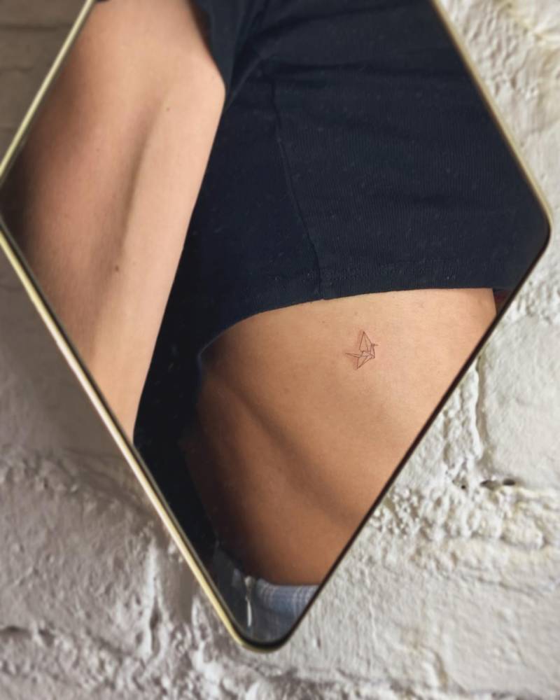 Fine line style origami crane tattoo located on the rib.