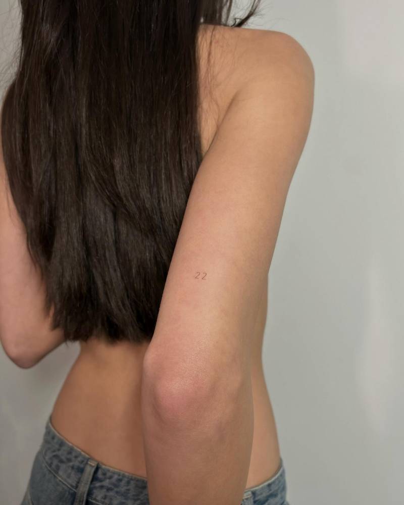 Little tattoo of the number "22" placed on the tricep.