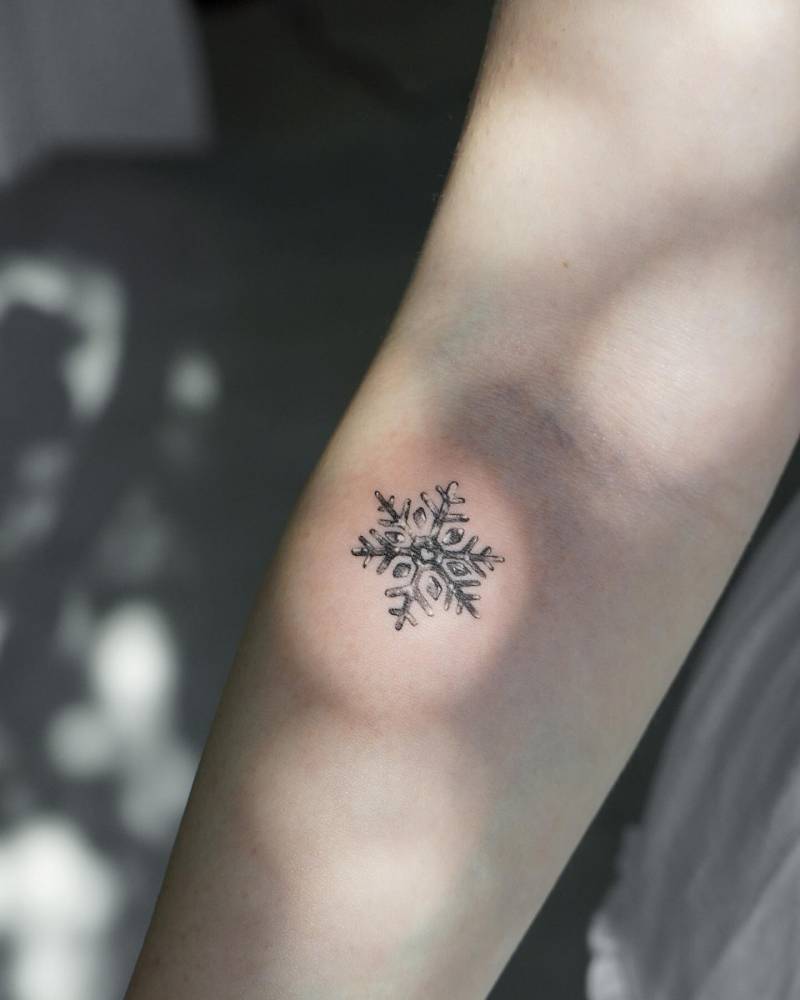 Micro-realistic style snowflake tattoo placed on the inner forearm.
