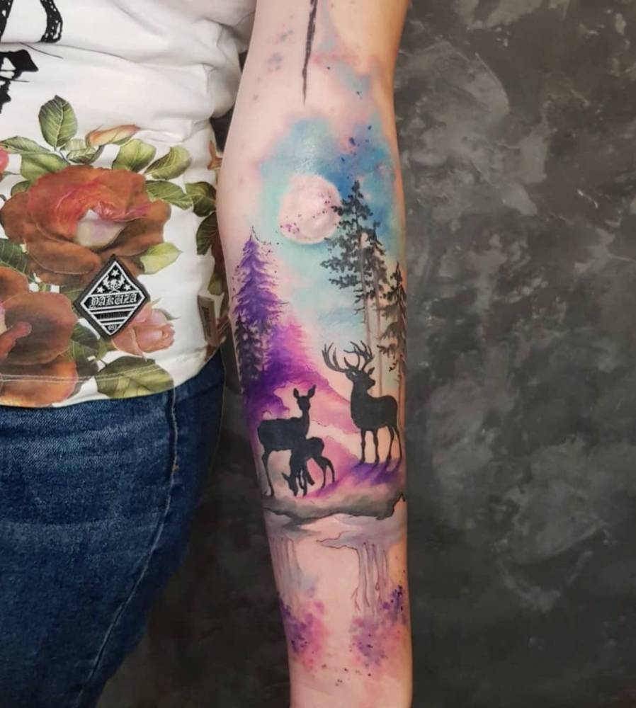 Forest and deers tattooed on the inner forearm, watercolor style.