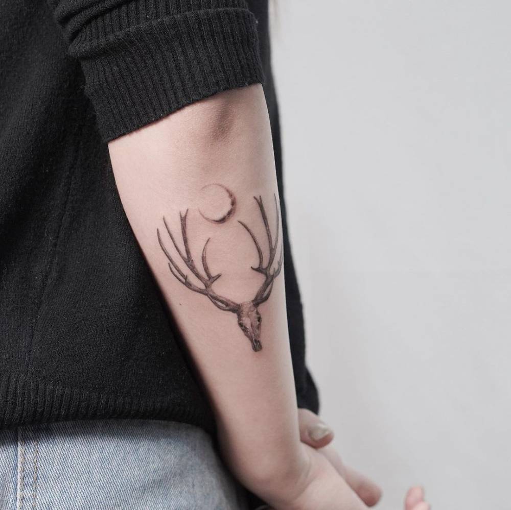 Deer skull tattoo located on the forearm, micro-realistic style.