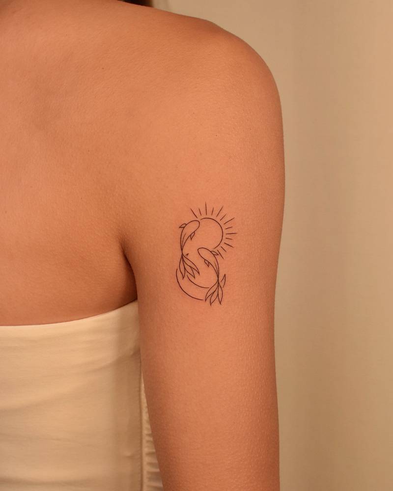 Two opposite fish tattoo located on the upper arm.