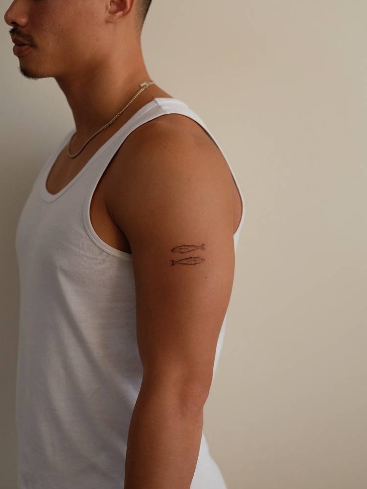 Two opposite fish tattoo located on the upper arm.